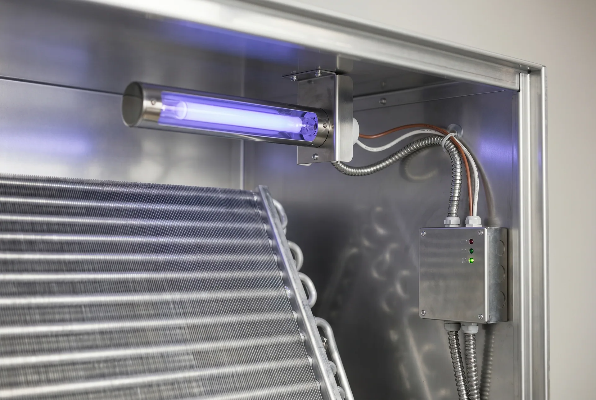 In-duct UV-C air purification light glowing inside an HVAC air handler near the evaporator coil.